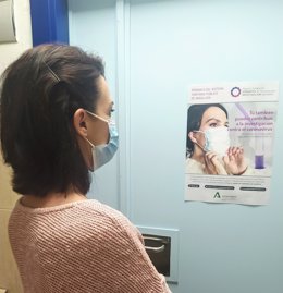 Una mujer mira un cartel de la campaña de donación de muestras covid-19.