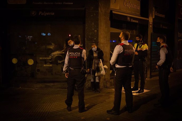 Varios mossos d'Esquadra paran a una persona durante un control durante el toque de queda impuesto por la crisis sanitaria del Covid-19 desde las 22.00 horas a las 6.00 del día siguiente, en Barcelona, Catalunya, (España), a 6 de noviembre de 2020.