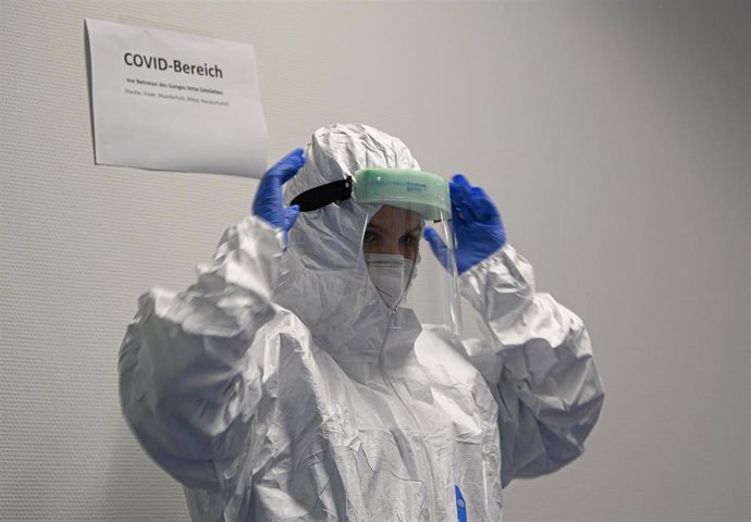 Un médico se coloca el equipo de protección