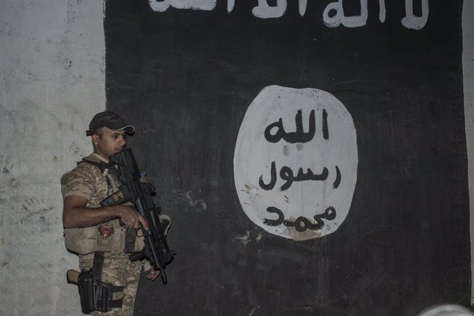 Un soldado iraquí junto a una bandera de Estado Islámico pintada en una pared en Mosul