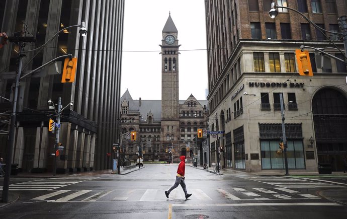 13 April 2020, Canada, Toronto: A man runs across an empty intersection of Bay street and Richmond amid restrictions on public life and non-esseential activities to curb the spreading of coronavirus. Photo: Richard Lautens/The Toronto Star via ZUMA Wire