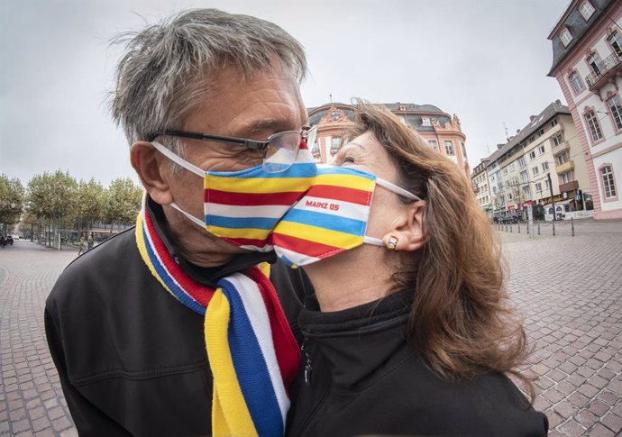 Dos artistas con mascarilla se besa en una plaza de Maguncia