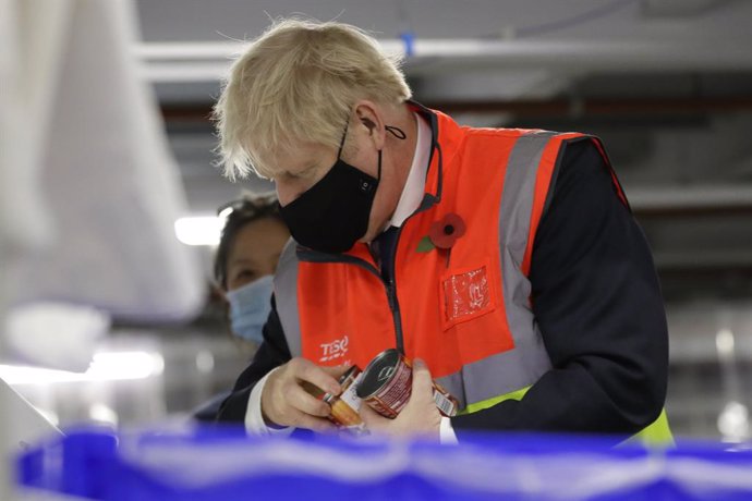 11 November 2020, England, Erith: UK Prime Minister Boris Johnson wearing a face mask loads produce into baskets during a visit to the Tesco Erith distribution Centre in south east London. Photo: Kirsty Wigglesworth/PA Wire/dpa