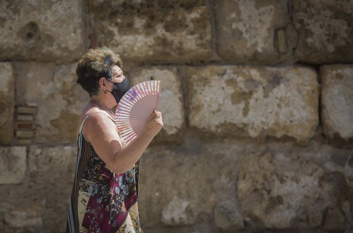 Una mujer se abanica mientras pasea por el entorno de la Catedral. En Sevilla (Andalucía, España), a 27 de agosto de 2020.