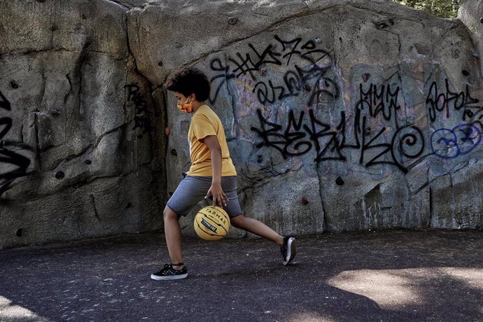 El niño actor y modelo Hugo Ndiaye, de 10 años, juega al baloncesto en un parque el primer día en el que los menores de 14 años de la Comunidad de Madrid pueden realizar paseos entre las 10 y las 13 horas y entre las 17 y las 21 horas, tras decidir la C