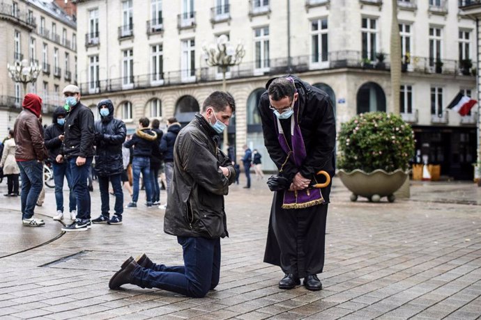 15 November 2020, France, Nantes: A Catholic priest listens to the confession of a believer during a gathering to call the reopening of places of worship as the national lockdown in France counties to stop the spread of the coronavirus. Photo: Sebastien