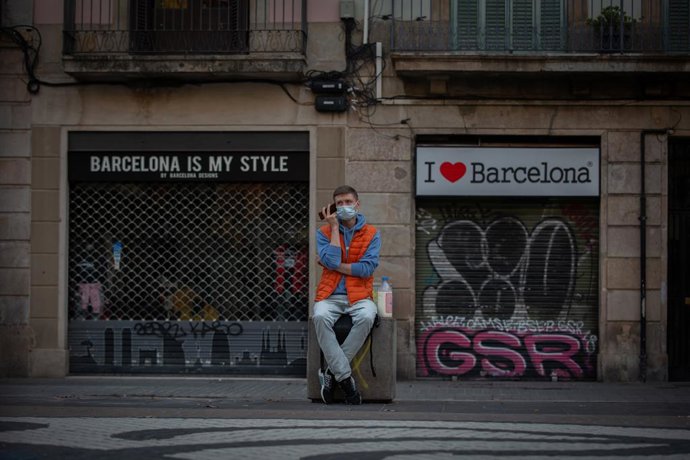 Un home escolta al seu telfon mbil enfront de dues botigues turístiques a Barcelona, Catalunya (Espanya), a 16 de novembre de 2020.