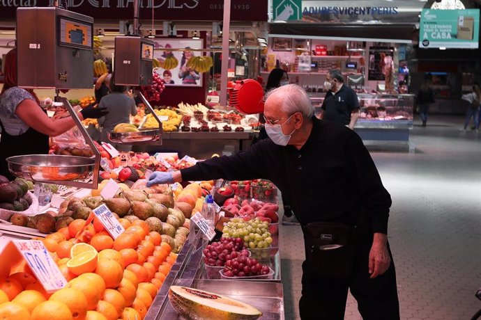 Un cliente señala la pieza de fruta que quiere en una frutería del Mercado Central de Valencia