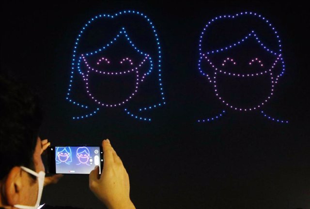 Drones dibujando con luces una pareja con mascarillas en Seúl