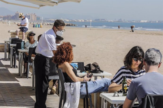 Varias personas disfrutan en la terraza de un bar junto a la playa después de que el Ministerio de Sanidad autorizara a que la totalidad de la Comunidad Valenciana pasase en su conjunto a la fase 1 de la desescalada. 