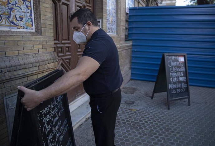 Un camarero quitando el cartel de su bar