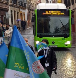 Dos jóvenes con la bandera gitana ante un autobús de Aucorsa con el lema alusivo al Día de los Gitanos de Andalucía, en una imagen de archivo.