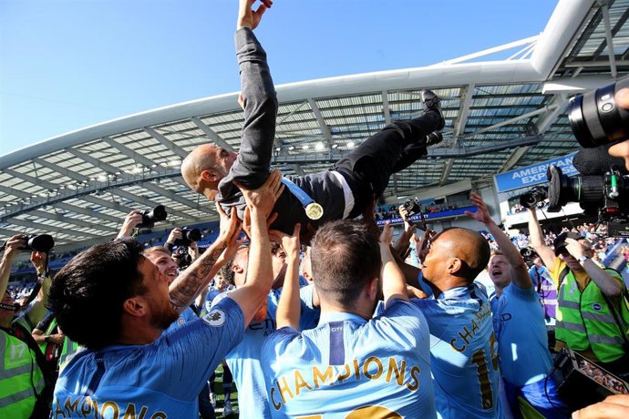 Manchester City manager Pep Guardiola is lifted up by his players whilst celebrating winning the title after the final whistle of the English Premier League soccer match between Brighton & Hove Albion and Manchester City at the AMEX Stadium.