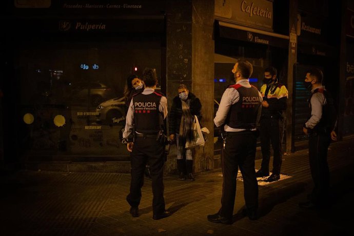 Varios Mossos d'Esquadra paran a una persona durante un control por el toque de queda impuesto a raíz de la crisis sanitaria del Covid-19 (Archivo)