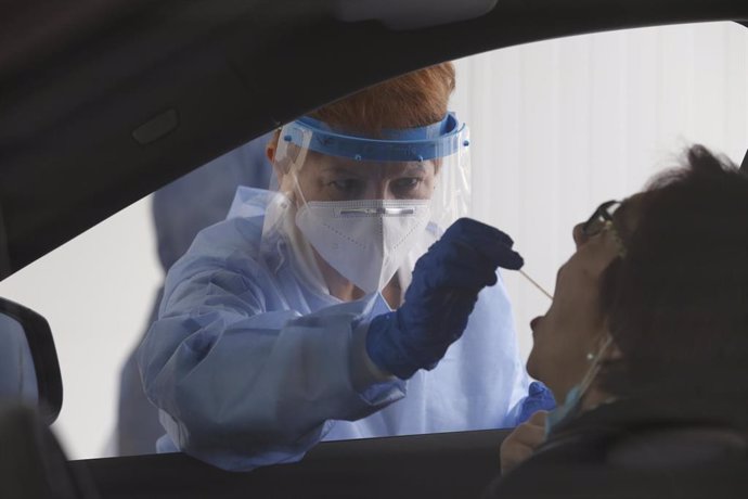 Una enfermera toma muestras a una paciente en un coche para realizar una PCR.