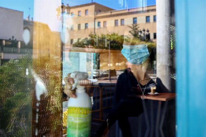 Una mujer desinfecta la cristalera de un establecimiento.