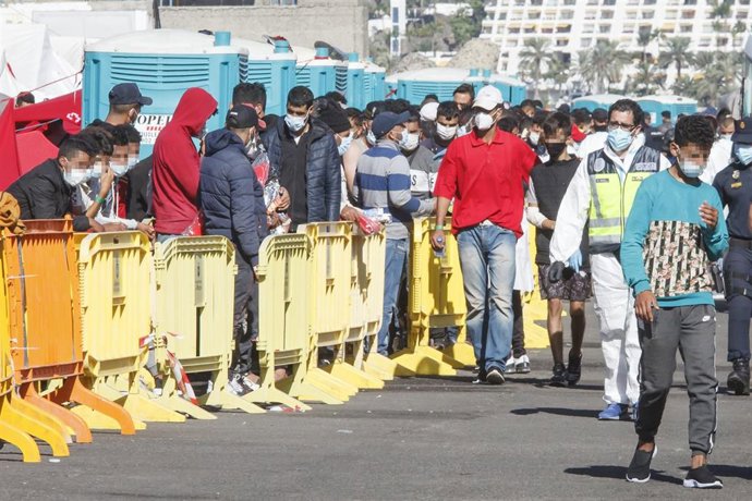 Varios inmigrantes hacen cola en el Muelle de Arguineguín, en Gran Canaria, Canarias (España), a 18 de noviembre de 2020. Más de 2.300 migrantes permanecen hacinados en este muelle tras pernoctar en el campamento que se instaló el pasado mes de agosto e
