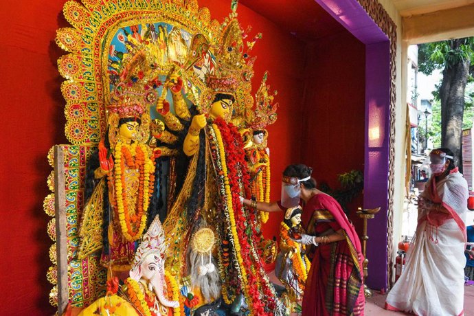 Mujeres con mascarilla hacen una ofrenda ante una escultura de la diosa Durga en Calcuta