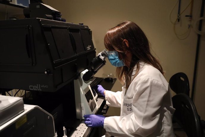 Una bióloga del Centro de Biología Molecular Severo Ochoa en el Campus de Cantoblanco de la Universidad Autónoma mira a través de un microscopio cuyas lentes están protegidas con plástico, durante el tercer día de su reapertura desde que se estableciero