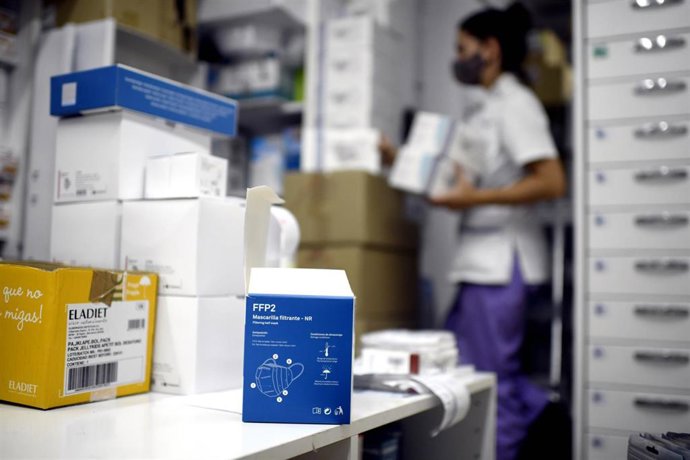 Vista de una de las cajas de test de antígenos para Covid-19 mientras una farmaceútica coloca varios productos en su farmacia, en Madrid
