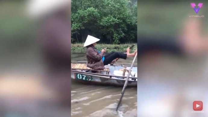 Esta mujer habla por teléfono mientras rema su embarcación usando sus pies