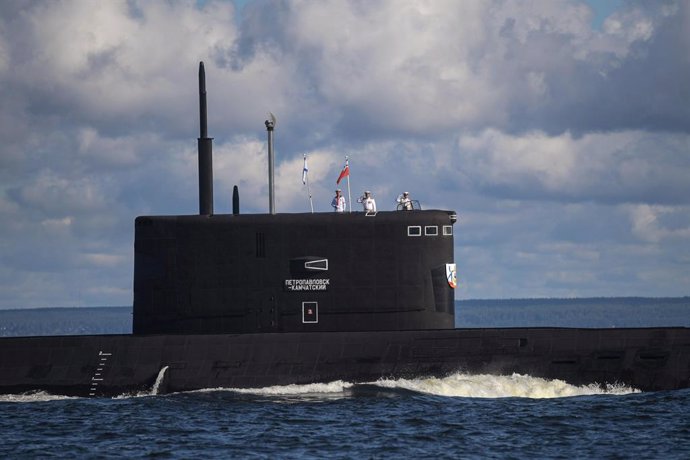 HANDOUT - 26 July 2020, Russia, Saint Petersburg: Russian navy officers stand attention on top of a submarine as it sails past during a military parade held on the occasion of the Russian Navy Day. Photo: -/Kremlin/dpa - ATTENTION: editorial use only an
