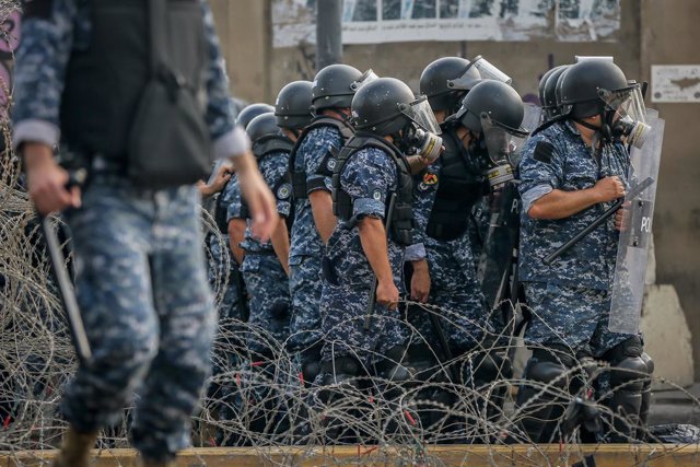 30 October 2020, Lebanon, Beirut: Riot police take cover as they protect the residence of the French ambassador in Beirut, during a demonstration against French President Emmanuel Macron's comments on Islam's prophet Muhammad cartoons. Photo: Marwan Naa