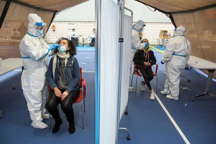 Varios trabajadores sanitarios totalmente protegidos realizan un test de antígenos de Covid-19 a dos vecinos el Complejo Deportivo El Plantío, en Burgos.