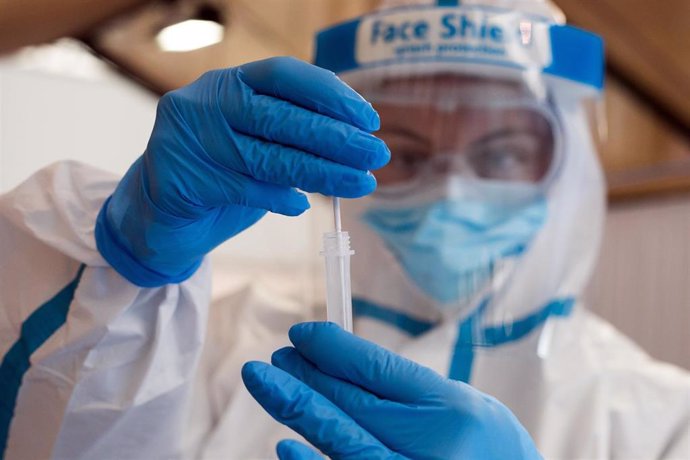 Una trabajadora sanitaria protegida muestra untest de antígenos.