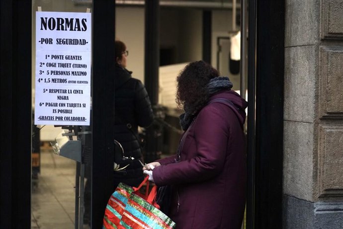 Una mujer coge su turno en una pescadería de Bilbao con normas por el estado de alarma 