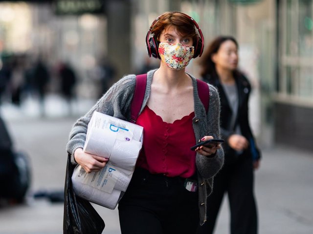 A woman wearing a protective mask carries a toilet paper package on the street on March 13, 2020 in New York City. President Donald Trump is expected to declare national emergency over coronavirus crisis today.
