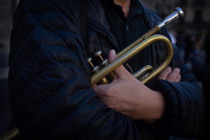 Un hombre sostiene una trompeta en una concentración contra las restricciones.