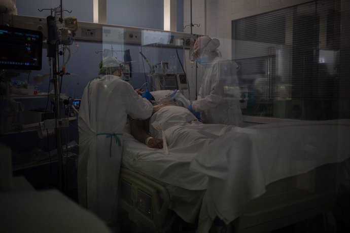Trabajadores sanitarios protegidos atienden a un paciente en una UCI.