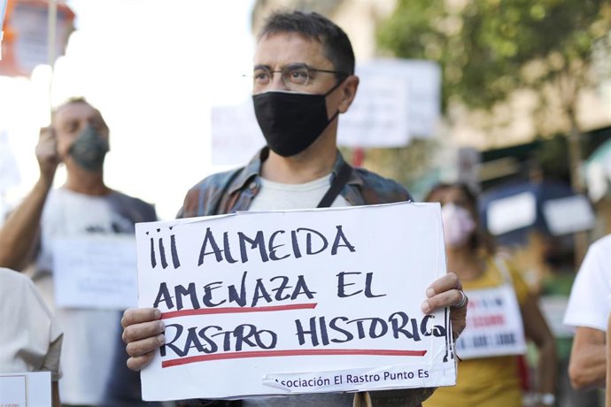 El cofundador de Podemos y director del Instituto 25 de Mayo del partido morado, Juan Carlos Monedero, sostiene una pancarta donde se puede leer "Almeida amenaza el Rastro Histórico".