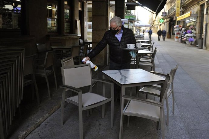 Un camarero desinfecta una mesa de su terraza de un establecimiento 