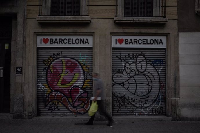 Un hombre camina al lado de dos tiendas turísticas en Barcelona, Catalunya (España), a 16 de noviembre de 2020.