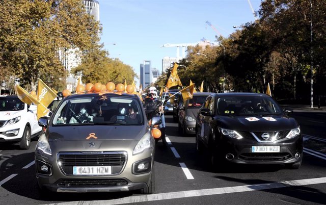 Varias personas muestran a través de sus coches banderas y globos de color naranja durante una manifestación de vehículos en apoyo a la educación concertada y contra la Ley Celaá.