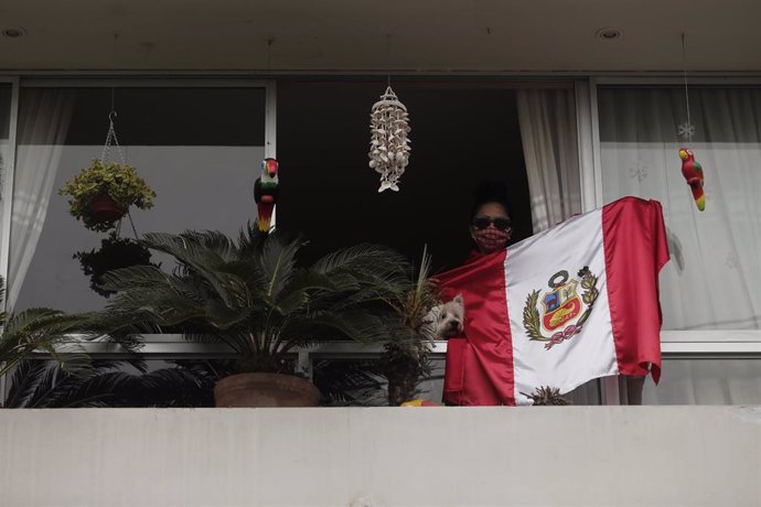 Una vecina de Lima alienta a sus vecinos desde el balcón de su casa con una bandera de Perú
