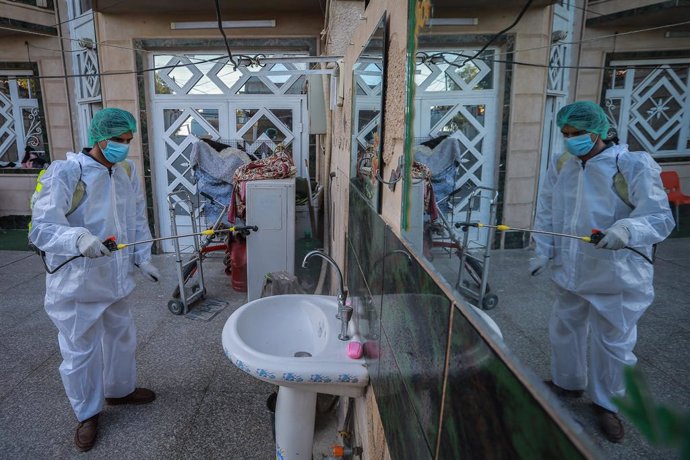 Un voluntario con en equipo de protección desinfecta una casa de Bagdad