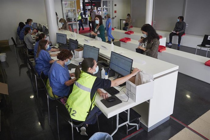 Trabajadores sanitarios protegidos atienden a los pacientes que acude para realizarse una extracción de muestras en el recinto ferial REFENA de Pamplona.