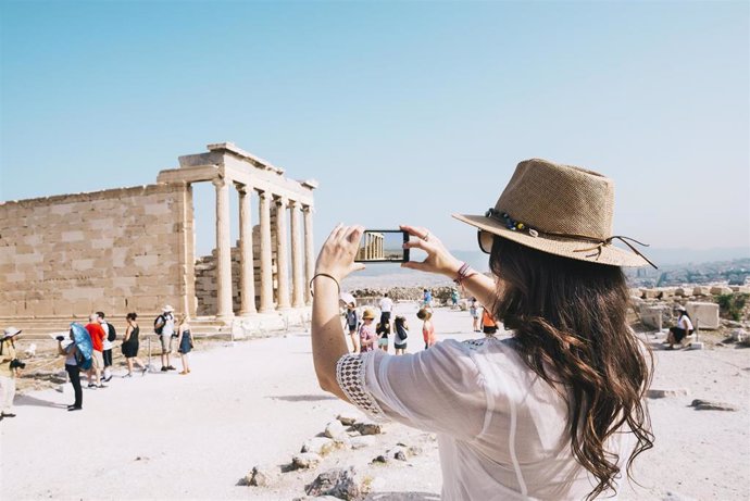 Un mujer hace una foto con su teléfono móvil en la Acropolis de Atenas (Grecia).