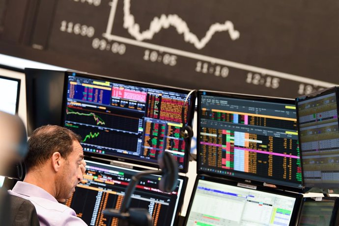 28 October 2020, Hessen, Frankfurt/Main: A stock trader observes his monitors on the floor of the Frankfurt Stock Exchange in front of the board with the falling Dax curve. Photo: Arne Dedert/dpa