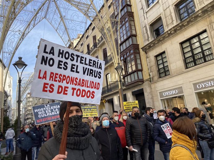 Uno de los asistentes a la manifestación en apoyo a la hostelería de Valladolid sostiene una pancarta durante el recorrido de la protesta a su paso por la calle Santiago de la capital vallisoletana.