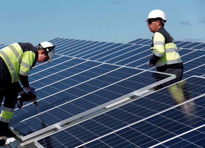 Dos operarios fijan paneles solares en la instalación