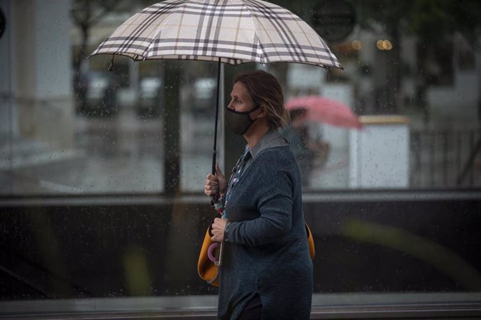 Una mujer se protege bajo su paraguas durante una jornada de lluvia