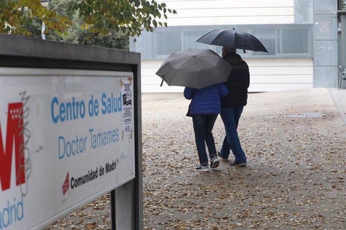 Dos personas caminan protegidas con paraguas por las inmediaciones del Centro de Salud Doctor Tamames, en la zona básica de salud de Doctor Mamames, en Coslada, Madrid (España), a 3 de noviembre de 2020. Doctor Tamames y Barrio del Puerto, ambas en Cosl