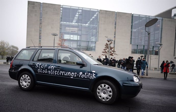25 November 2020, Berlin: A fireman at the wheel removes a car, which crashed stands in the gate of the Federal Chancellery, with inscription on the door : Stop the policy of globalization. Photo: Michael Kappeler/dpa