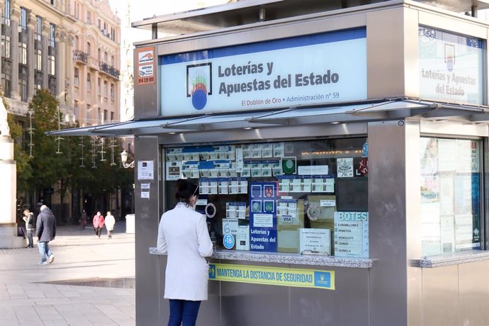 La administración de Lotería de la Puerta del sol atiende a un cliente, en Madrid, España, a 10 de noviembre de 2020. Debido a las medidas de limitación de movilidad para hacer frente a la pandemia del COVID-19, los comercios y locales de restauración c