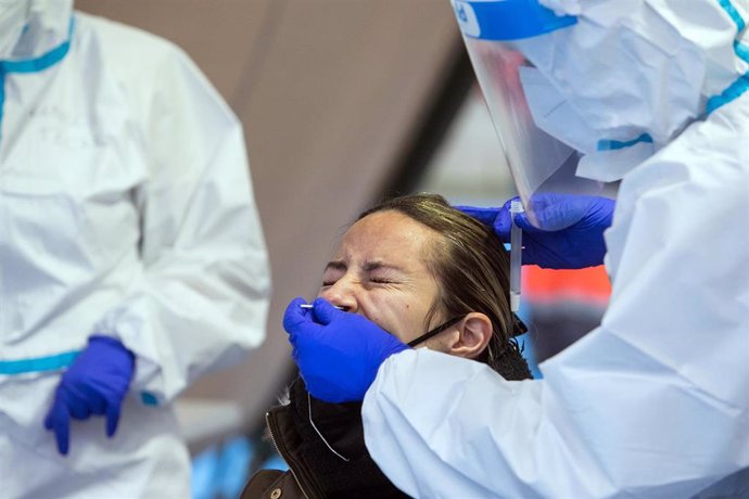 Un trabajador sanitario totalmente protegido realiza un test de antígenos de Covid-19