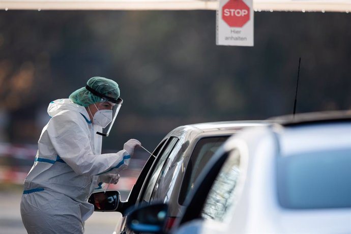 25 November 2020, Baden-Wuerttemberg, Nuertingen: An employee at a drive-thru testing centre takes a swab from a car driver for a coronavirus test. Photo: Tom Weller/dpa
